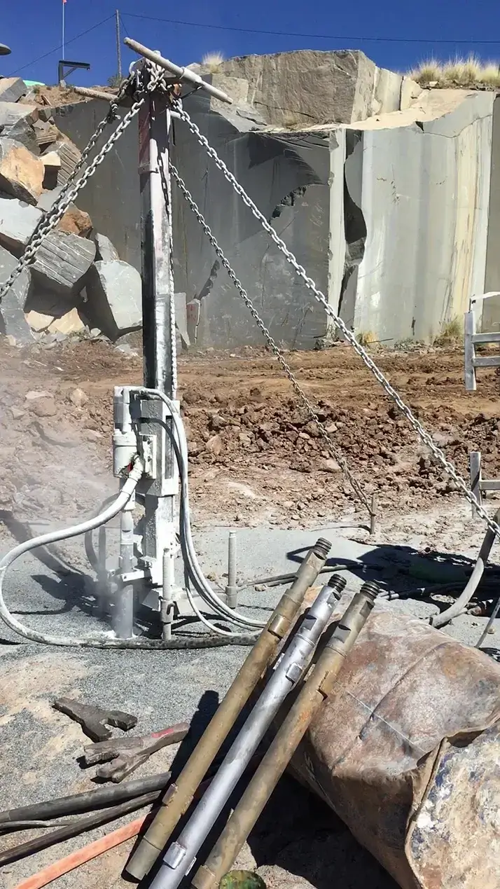 DTH drilling machine executing a perfectly plumb vertical deep hole from the top of a marble bench