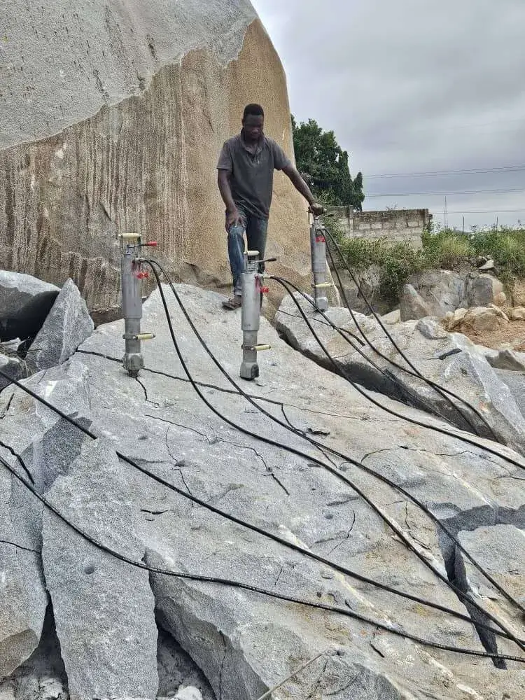 Hydraulic rock splitter cracking a granite boulder