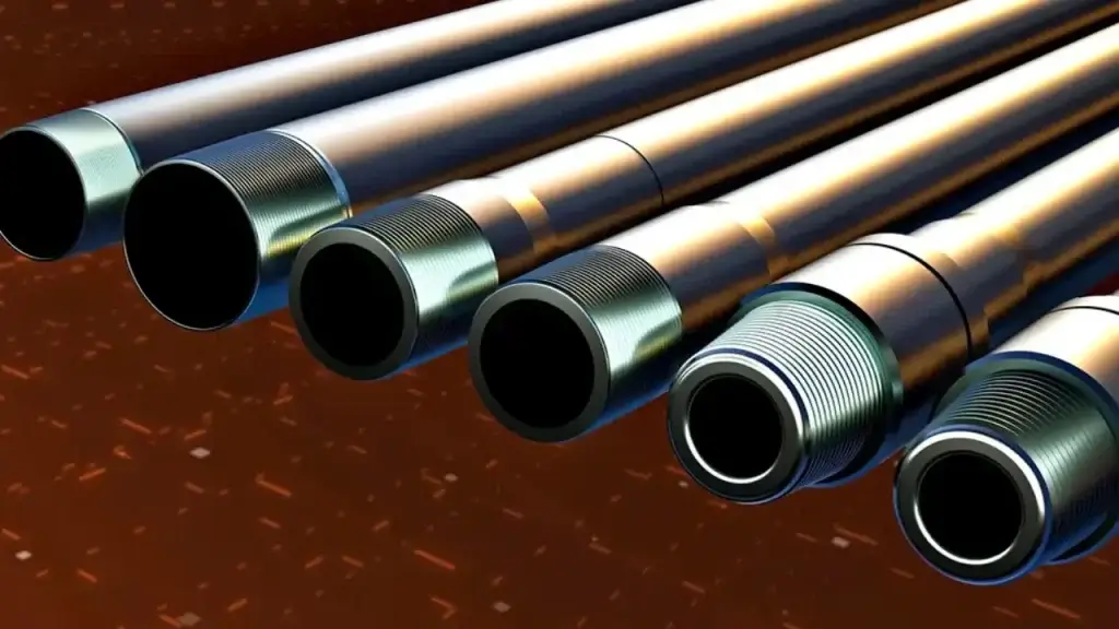 Operator using a wire brush to clean old grease from an API thread while nearby drill rods are fitted with plastic thread protectors